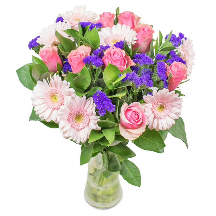 An exuberant, elegantly structured floral bouquet stands proudly in a clear glass vase, its design echoing the dynamic energy of Bayswater's leafy avenues. The centerpiece features an artful mix of seven to nine medium-pink roses, their velvety petals either tightly nestled or just unfurling in perfect spirals, embodying classic romance. These are complemented beautifully by five to seven pale pink gerbera daisies, each with a large, round bloom and nearly white centers that glow beneath natural daylight, reminiscent of blooms found at Paddington Street Gardens. Dotted amongst the bouquet are vibrant clusters of rich purple filler flowers-likely statice-which lend textural drama and a pop of contrasting colour, evoking the eclectic blend of cultures and colours found along Queensway. Glossy, deep green foliage provides both structure and a sense of freshness, enhancing the vibrancy of the florals. The crystal-clear vase reveals a tangle of stems and fresh water, emphasizing the arrangement's just-cut vitality. Perfect for marking birthdays, anniversaries, or simply brightening local homes and offices, this composition conveys heartfelt celebration and affection-a signature of Flowers Bayswater's commitment to artistry and community spirit.